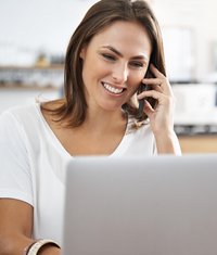 Frau sitzt telefonierend vor Computer